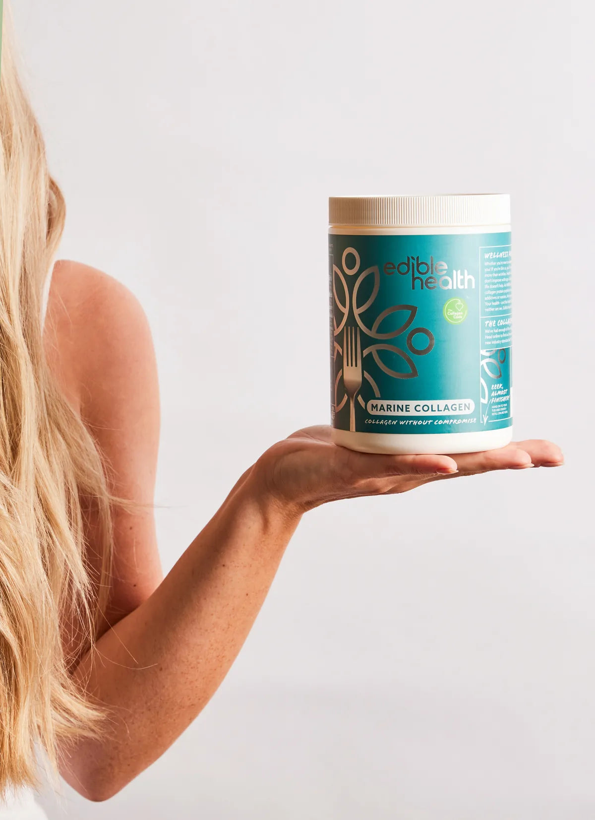 Holding a tub of Edible Health marine collagen